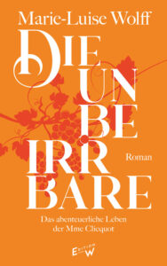Das Cover von »Die Unbeirrbare« zeigt den Titel in einer verspielten, weißen Serifenschrift. Darum rankt sich in orangerot eine grafische Weinranke. Der Hintergrund ist orange.